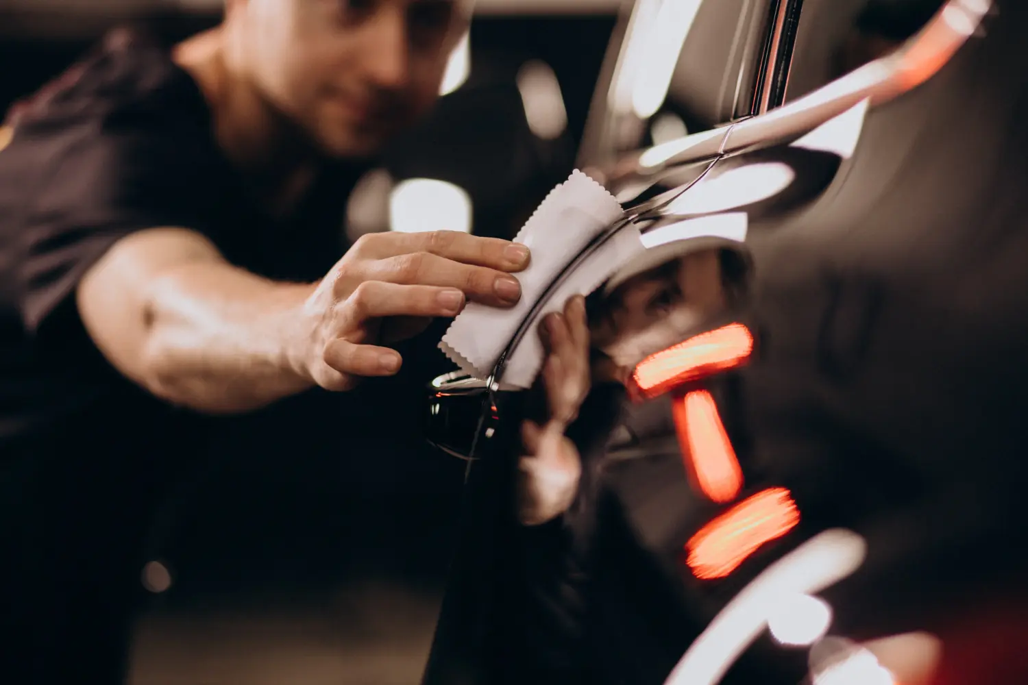 A Person Cleaning A Black Color Car